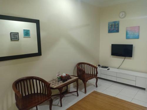 uma sala de estar com duas cadeiras, uma mesa e uma televisão em KH Homestay Comfy N Calm em Seri Manjung