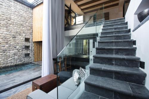 a glass staircase in a house with a stone wall at Clay Beach Samui - Beachfront Villas in Amphoe Koh Samui