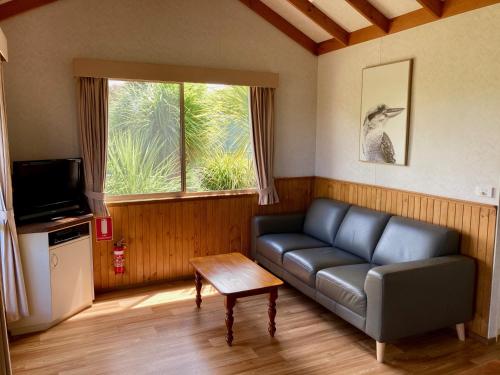 a living room with a couch and a table at Daysy Hill Country Cottages in Port Campbell