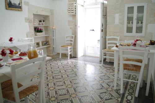 a dining room with white chairs and a tile floor at B&B Aia Vecchia in Cisternino