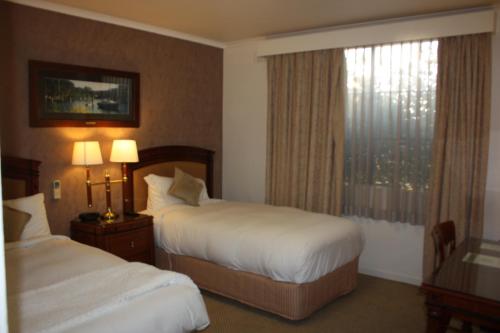 a hotel room with two beds and a window at Country Plaza Motel in Queanbeyan