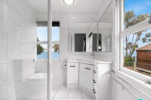 a white bathroom with a shower and a sink at Golden Sands at Beachmere in Beachmere