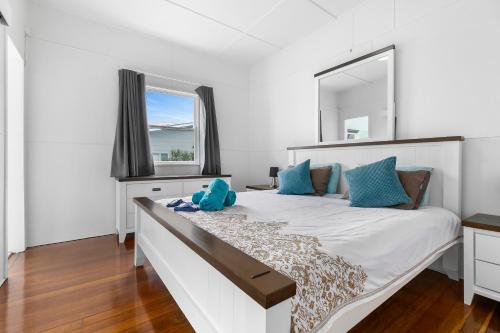 a white bedroom with a large bed with a large mirror at Golden Sands at Beachmere in Beachmere