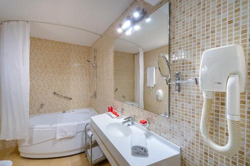 a bathroom with a sink and a tub and a mirror at AZIMUT Hotel Siberia in Novosibirsk