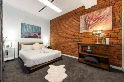 - une chambre avec un mur en briques et un lit dans l'établissement StayCentral - Heritage Warehouse Retreat Melbourne, à Melbourne
