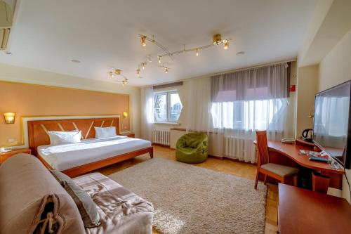 a bedroom with a bed and a desk and a television at AZIMUT Hotel Siberia in Novosibirsk