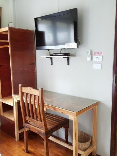 a tv on a wall with a wooden table and a chair at Bangkok Check Inn @Chareon Krung in Bangkok