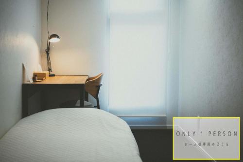 Pokój z łóżkiem, biurkiem i oknem w obiekcie RAK KIYOMIZU - 1人旅専用hostel w mieście Kioto