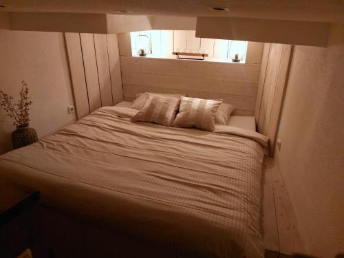 een bed in een kleine kamer met een raam bij Het Waterhotel in Heerenveen