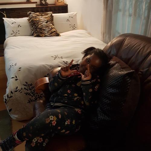 a woman laying on a couch with a cell phone at The Royal Princess B&B on Malibongwe Drive in Johannesburg