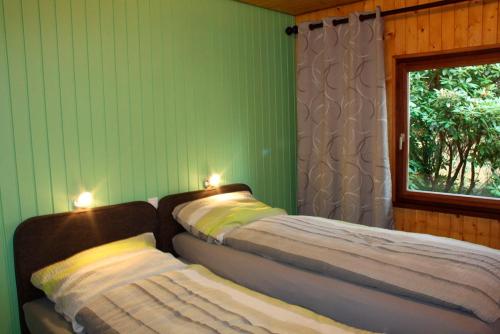 two beds in a room with green walls and a window at Ortheide 68 in Böddenstedt
