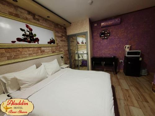 a bedroom with a white bed and a brick wall at Aladdin Hotel Beer Sheva in Beer Sheva
