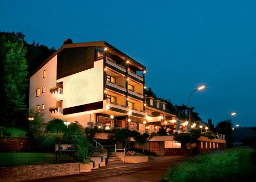 un grand bâtiment avec des lumières allumées la nuit dans l'établissement Hotel Hegenbarths, à Cochem