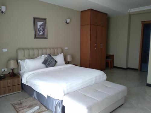 a bedroom with a large white bed and a cabinet at Daisy Hotel in Addis Ababa