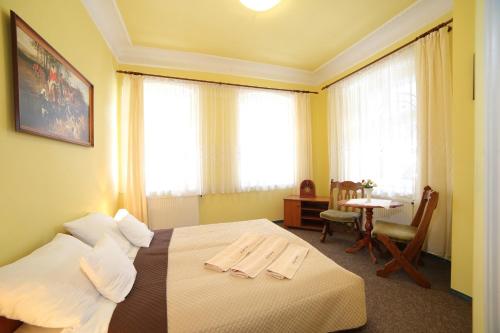 pokój hotelowy z łóżkiem, stołem i oknami w obiekcie "Willa Millennium" w Międzygórzu