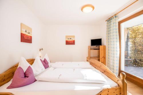 Schlafzimmer mit einem Bett mit lila und weißen Kissen in der Unterkunft Bnb Lettnerhof Terrace Family Suite in Welsberg-Taisten