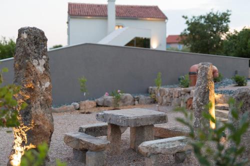 a stone bench and a table in a garden at Luxury Jerini Estate in Krk