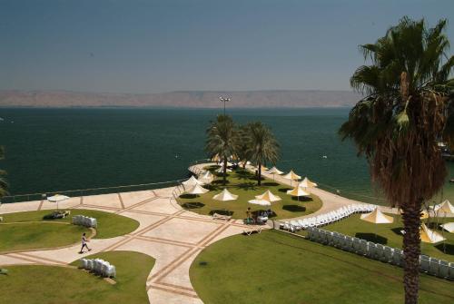 a park with yellow and white umbrellas and the ocean at Gai Beach Hotel in Tiberias