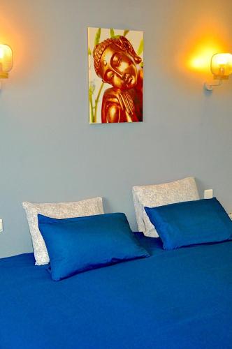 un lit avec des draps bleus et une peinture sur le mur dans l'établissement VILLA - BAIN NORDIQUE SPA EXTÉRIEUR - POÊLE FINLANDAIS - PISCINE - Gaillac, à Montans