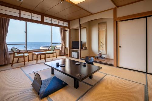 a living room with a table and a view of the ocean at Ikkyu -Seaside Hotel- in Tsuruoka