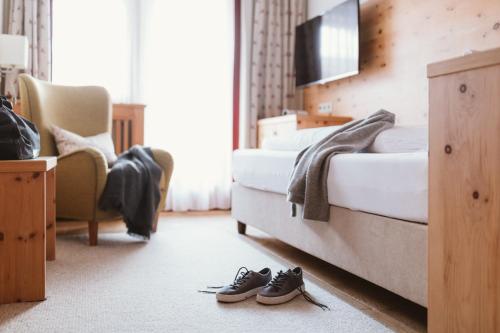 a bedroom with a bed and a pair of shoes at Gartenhotel Linde 4 Sterne Superior in Ried im Oberinntal