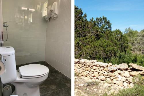 a bathroom with a toilet and a stone wall at La Casita Yolanda, ideal parejas - Formentera Natural in Sant Ferran de Ses Roques