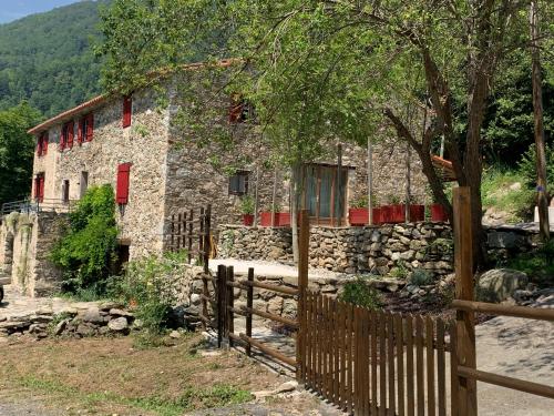 a stone house with red windows and a fence at Mas Graffouil in Prats-de-Mollo-la-Preste