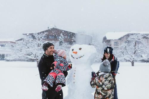 a man and a woman standing next to a snowman at Gartenhotel Linde 4 Sterne Superior in Ried im Oberinntal