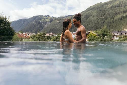 a man and a woman sitting in the water at Gartenhotel Linde 4 Sterne Superior in Ried im Oberinntal