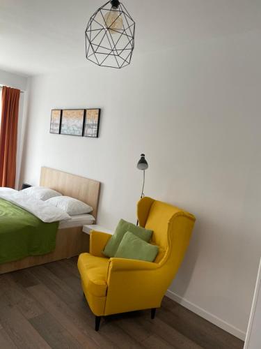 Un dormitorio con una silla amarilla y una cama en Apartcentral, en Baia Mare