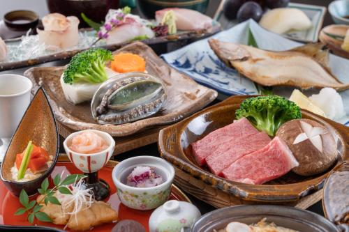 a table topped with plates of food with vegetables and meats at Ikkyu -Seaside Hotel- in Tsuruoka