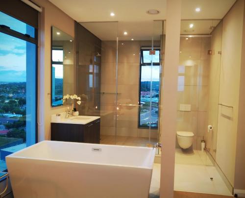 a bathroom with a tub and a toilet and a window at Menlyn Residence - Luxury Business Apartment in Pretoria