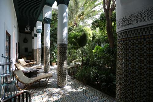 une véranda avec des chaises, une table et des arbres dans l'établissement Palais Riad Lamrani, à Marrakech