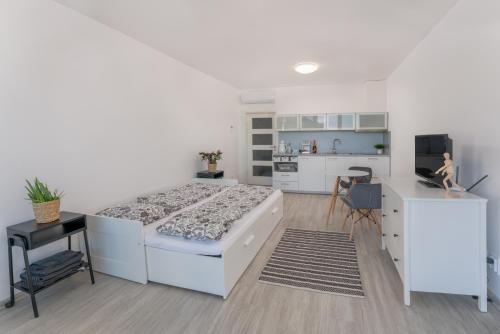 a white bedroom with a large bed and a kitchen at Apartmán Šantovka in Olomouc