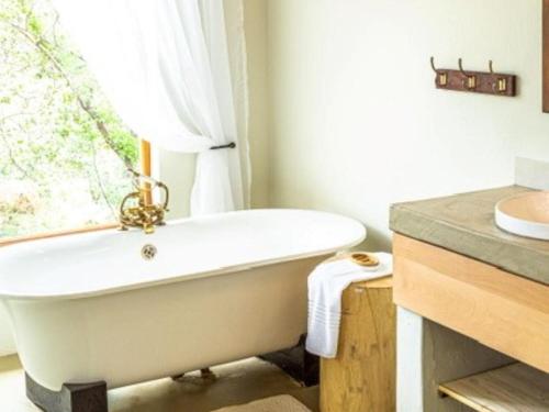 a white bath tub in a bathroom with a window at Eclectic Safari Lodge in Mabula