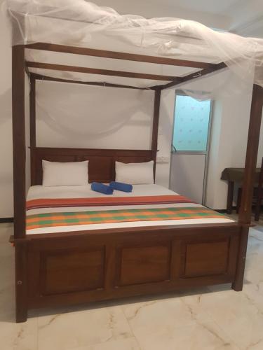 a bedroom with a wooden bed with a canopy at Sea Port Hiriketiya in Hiriketiya