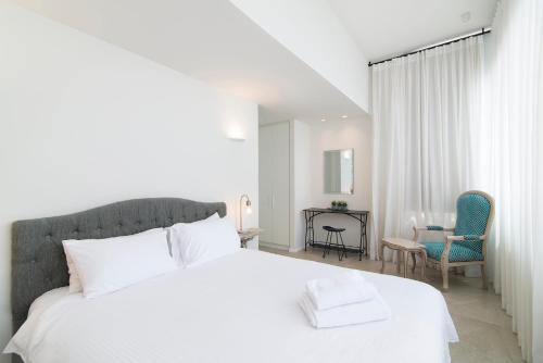 Un dormitorio con una cama blanca y dos sillas. en TLV Center by TLV2RENT, en Tel Aviv