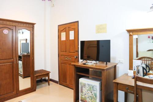 a living room with a tv and a desk with a television at Ban Ao Thong in Trang