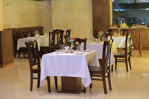 a dining room with tables and chairs with white table cloth at Daisy Hotel in Addis Ababa