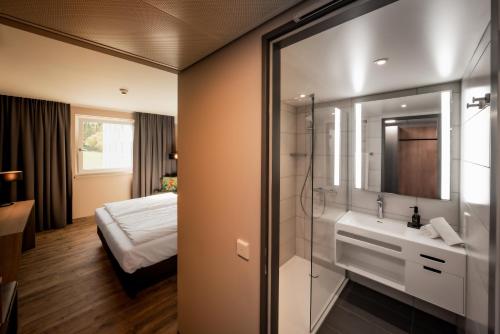 baño con lavabo y 1 cama en una habitación en LOGINN Hotel Stuttgart Zuffenhausen, en Stuttgart