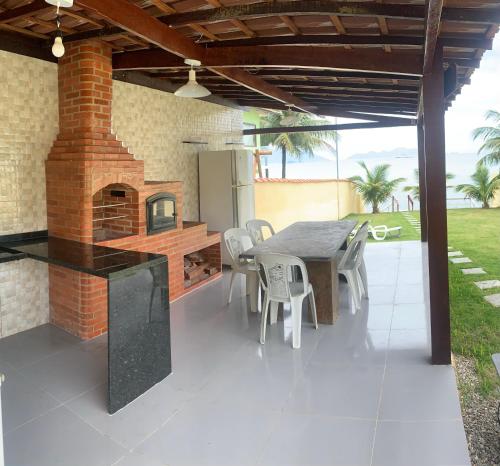 an outdoor kitchen with a table and a brick oven at Casa para temporada com vista para o Mar in Mangaratiba