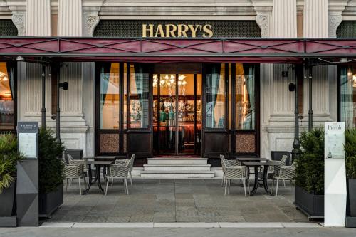 a harryties store with tables and chairs in front of a building at Grand Hotel Duchi d'Aosta in Trieste