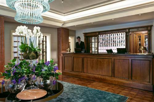 a man standing in a lobby with a reception desk at Grand Hotel Duchi d'Aosta in Trieste