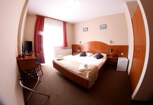 a hotel room with a large bed and a desk at Hotel Zagi in Oroslavje