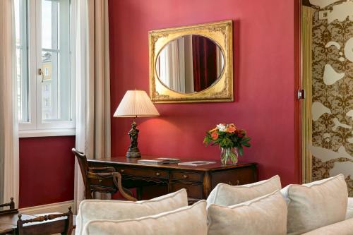 a red room with a desk and a mirror at Grand Hotel Duchi d'Aosta in Trieste