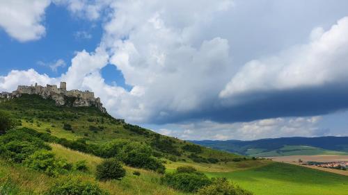 a castle on top of a green hill at Apartmán AQUAPARK - Hotel Bešeňová in Bešeňová