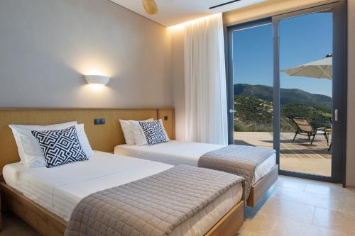 two beds in a hotel room with a balcony at Blooms of Sivota Bay - Luxury villas with private heated pool in Sivota