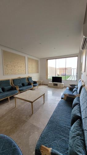 a living room with blue couches and a tv at شاليه المنى - الخبر - للعائلات in Al Khobar
