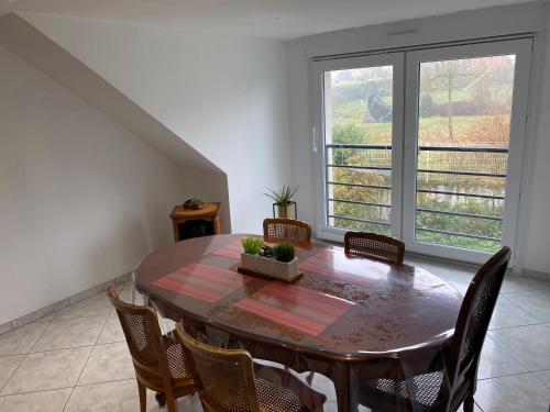 une salle à manger avec une table et des chaises et une fenêtre dans l'établissement Appartement des ruisseaux, à Macheren