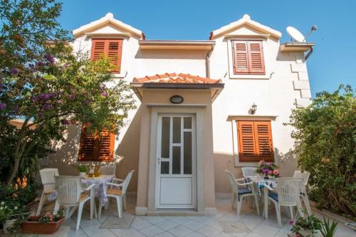 a white house with tables and chairs in front of it at Apartments Longo in Supetar